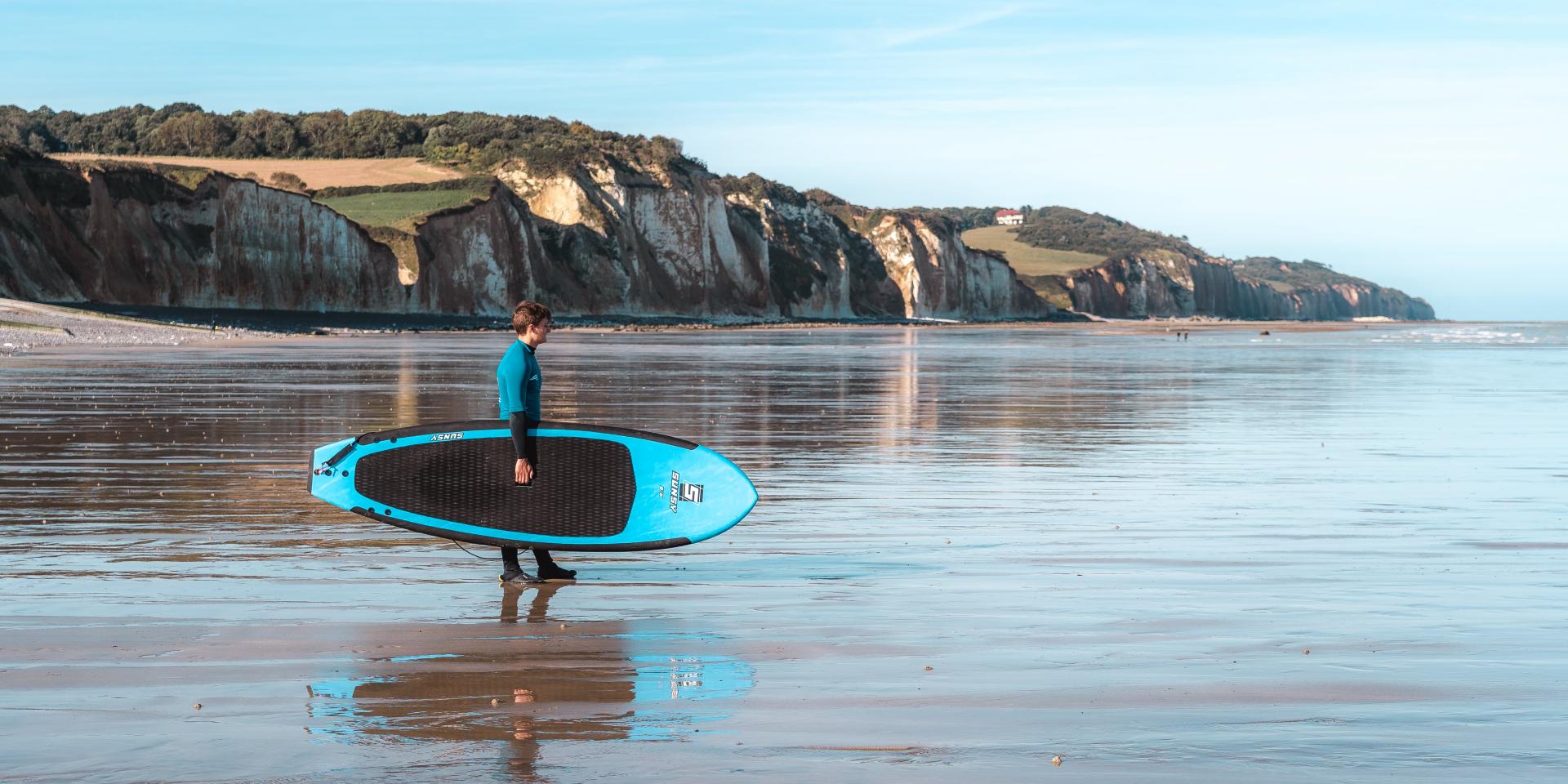 Jeune surfeur face aux falaises