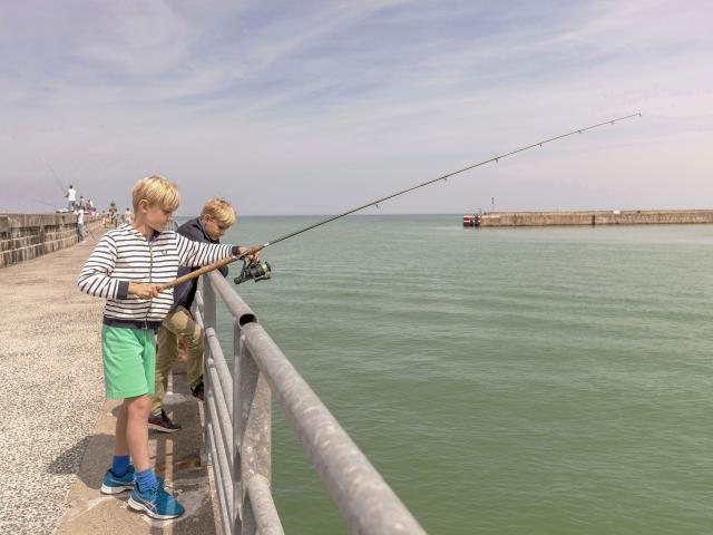 Deux jeunes garçons pêchant avec une canne sur la jetée