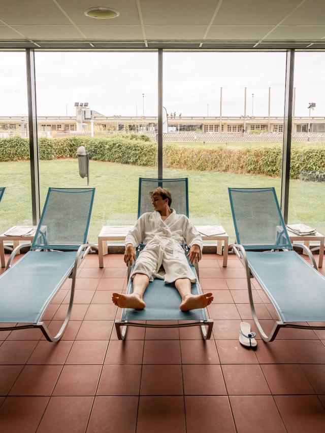 Jeune homme en peignoir se reposant sur un fauteuil au spa