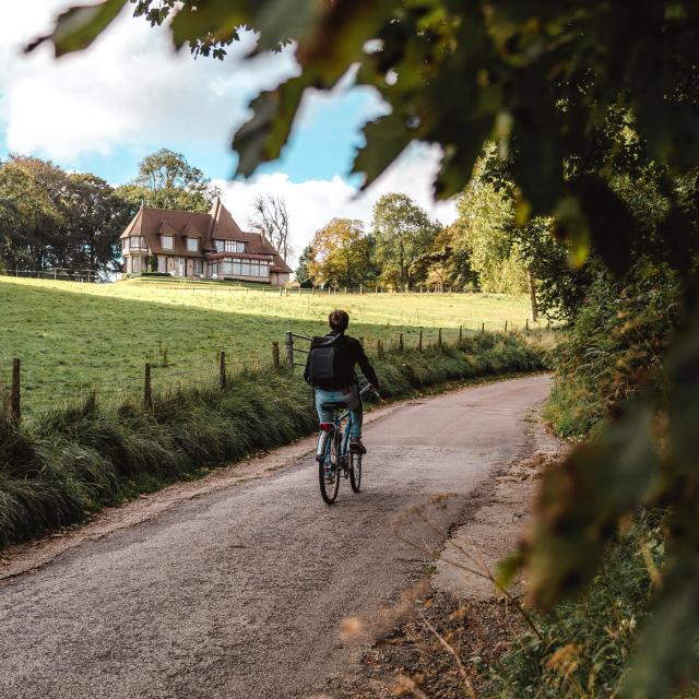 Jeune homme à vélo devant un manoir dans le village de Varengeville-Sur-Mer.