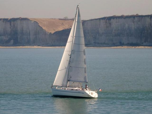 Voilier blanc naviguant au large des falaises