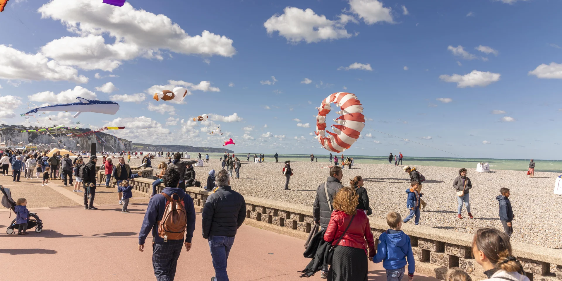 Une foule qui se promène sur le front de mer avec des cerfs-volants au-dessus d'eux