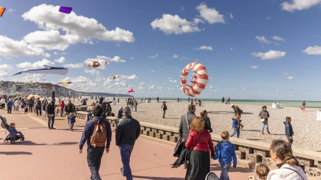 Une foule qui se promène sur le front de mer avec des cerfs-volants au-dessus d'eux