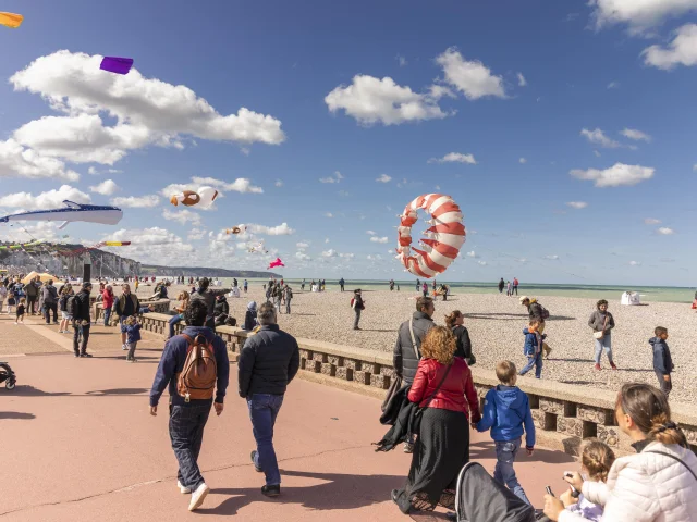 Une foule qui se promène sur le front de mer avec des cerfs-volants au-dessus d'eux
