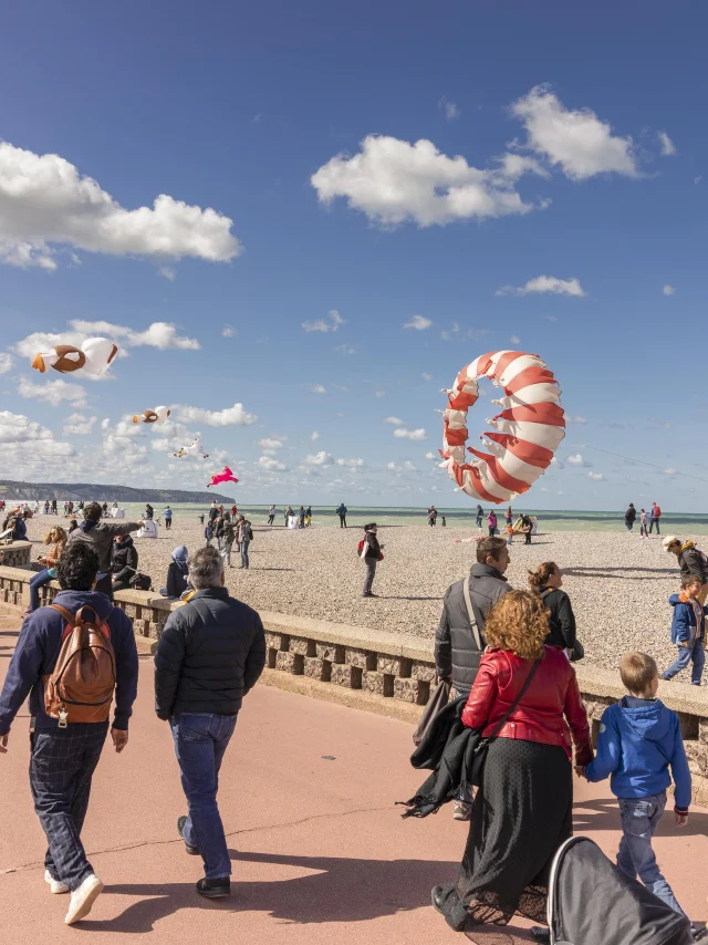 Une foule qui se promène sur le front de mer avec des cerfs-volants au-dessus d'eux