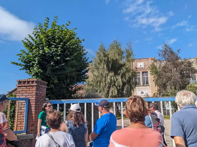 Groupe de visiteurs écoutant un guide devant le portail d'un bâtiment