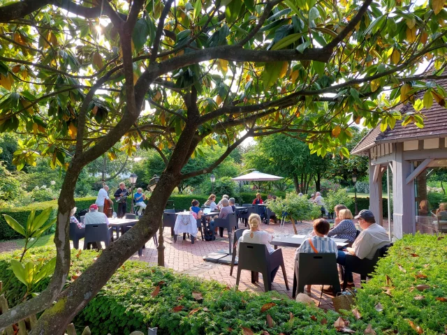 Groupes de personnes sur une terrasse écoutant un groupe de musique au parc du Colombier