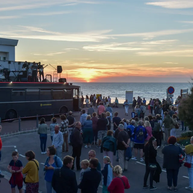 Coucher de soleil à la plage de Puys vu par des dizaines de personnes dans une atmosphère collective avec un groupe de musique