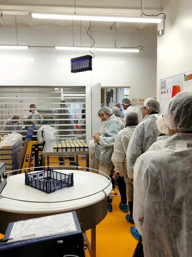 Un groupe de personnes équipées de charlottes et de vêtements de protection dans l'une des salles de conception du caramel de pommes dieppois
