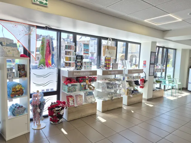 Boutique de l’Office de Tourisme de Dieppe proposant des souvenirs, cartes et spécialités locales, avec vue sur le centre-ville à travers les grandes baies vitrées.