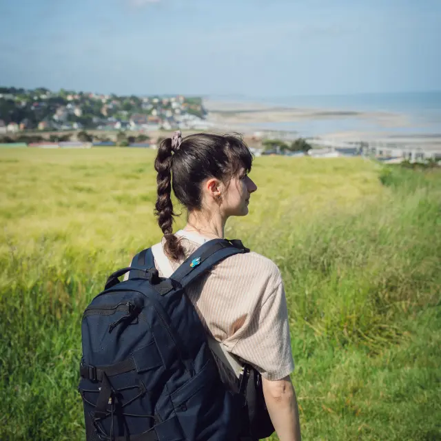 Vue sur Pourville-sur-Mer depuis les hauteurs, où un randonneur contemple la plage, les falaises et le littoral, illustrant une balade entre mer et campagne.