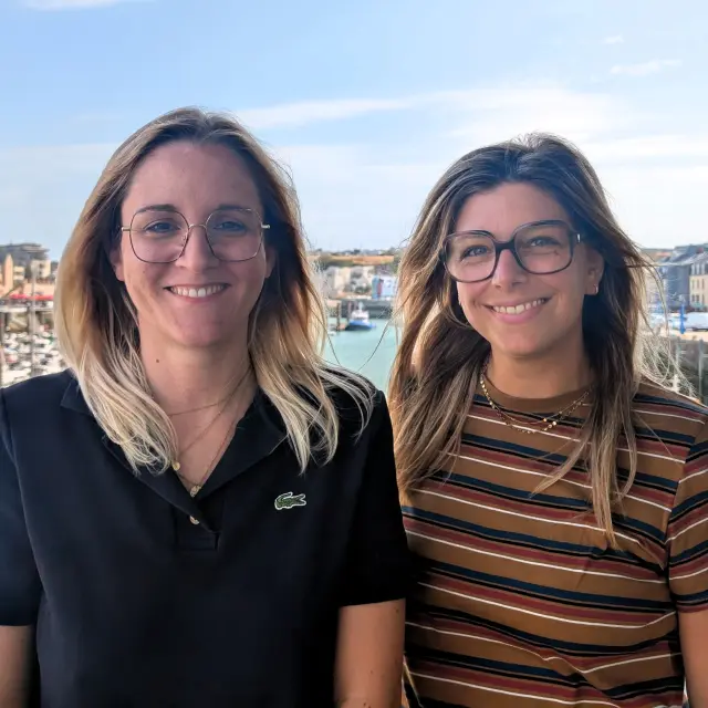 Rachel et Clélia, commerciales de l’Office de Tourisme, posent devant le port de plaisance de Dieppe et ses voiliers amarrés.