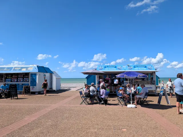 Glaciers et terrasses sur le front de mer de Dieppe, où visiteurs et familles font une pause face à la plage de galets.