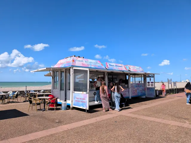 Glaciers et terrasses sur le front de mer de Dieppe, où visiteurs et familles font une pause face à la plage de galets.