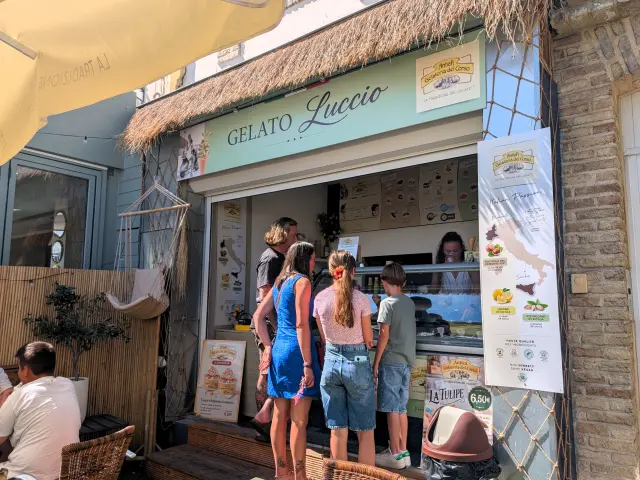 Famille choisissant des glaces au comptoir de Gelato Luccio, glacier du quai de Dieppe, dans une ambiance estivale.