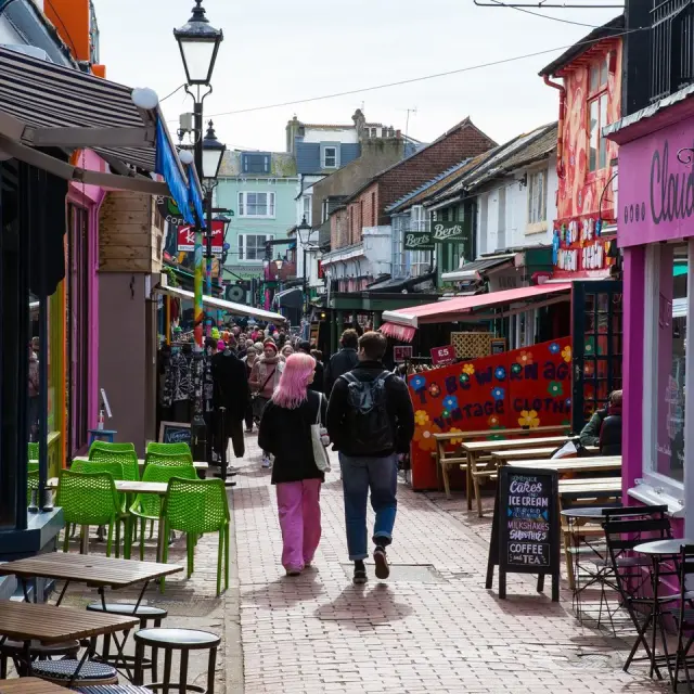 Rue animée du quartier North Laine à Brighton, bordée de boutiques colorées, de cafés et de terrasses fréquentées par les visiteurs.