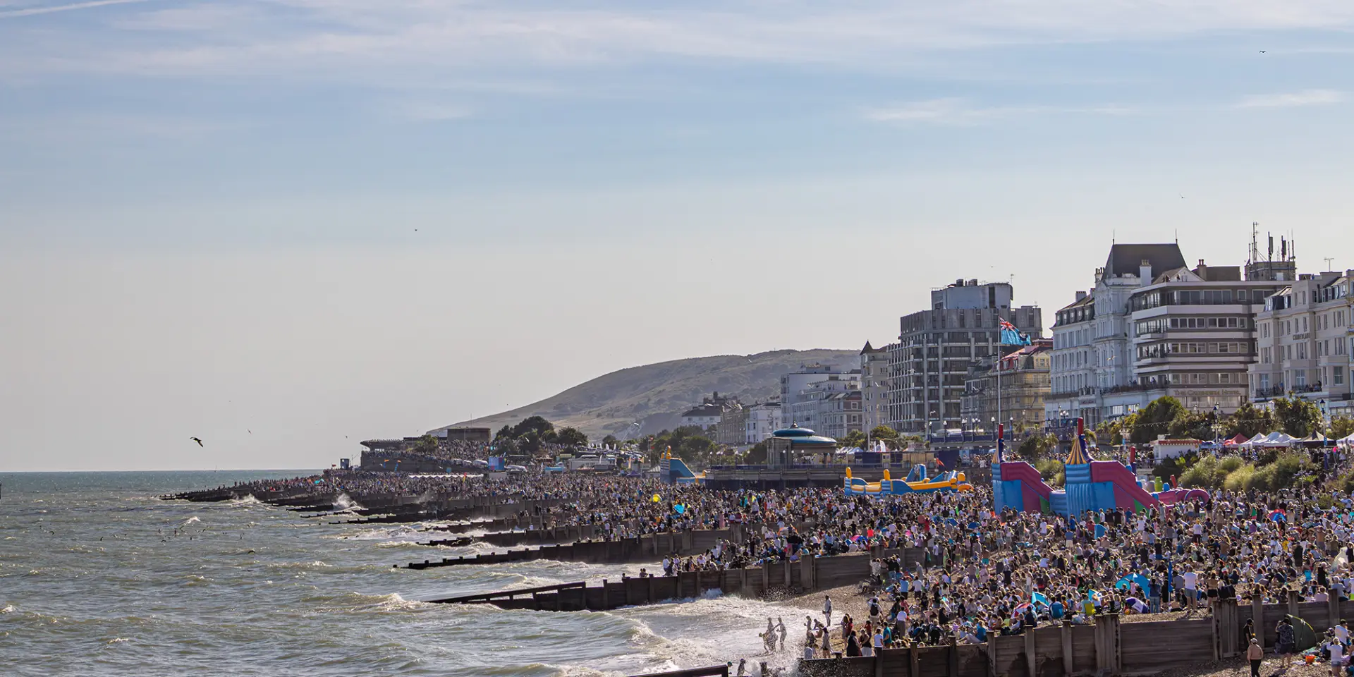La patrouille des Red Arrows survole le front de mer d’Eastbourne en traçant des fumées rouges, blanches et bleues devant une foule nombreuse.